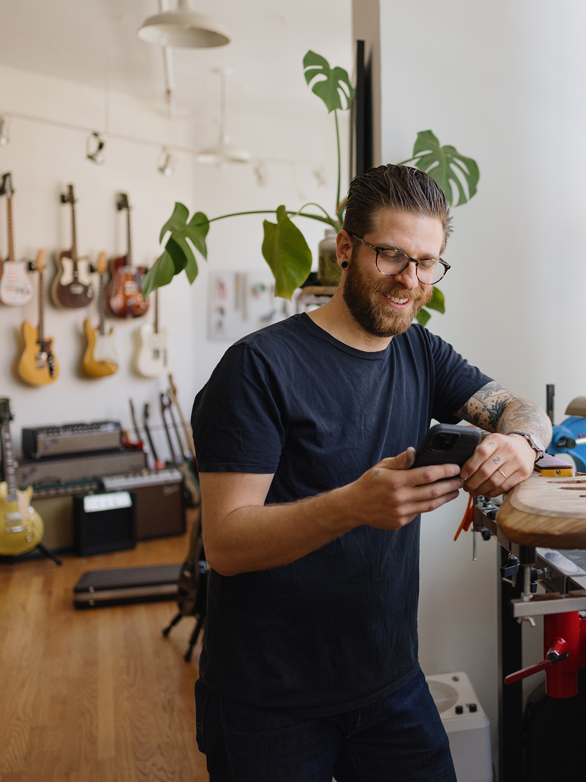 Giovane commerciante con smartphone nel suo negozio di strumenti musicali